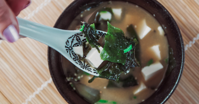 Na obrázku sa nachádza pohľad zhora na lyžičku, v ktorej je Miso polievka